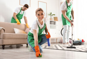 three Wanny Cleaning professionals working in a client's living room. they are vacuuming, cleaning the carpet, and the hard wood floors