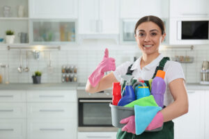 a cleaner from Wanny Cleaning LLC giving a thumbs up and holding a basket of cleaning supplies